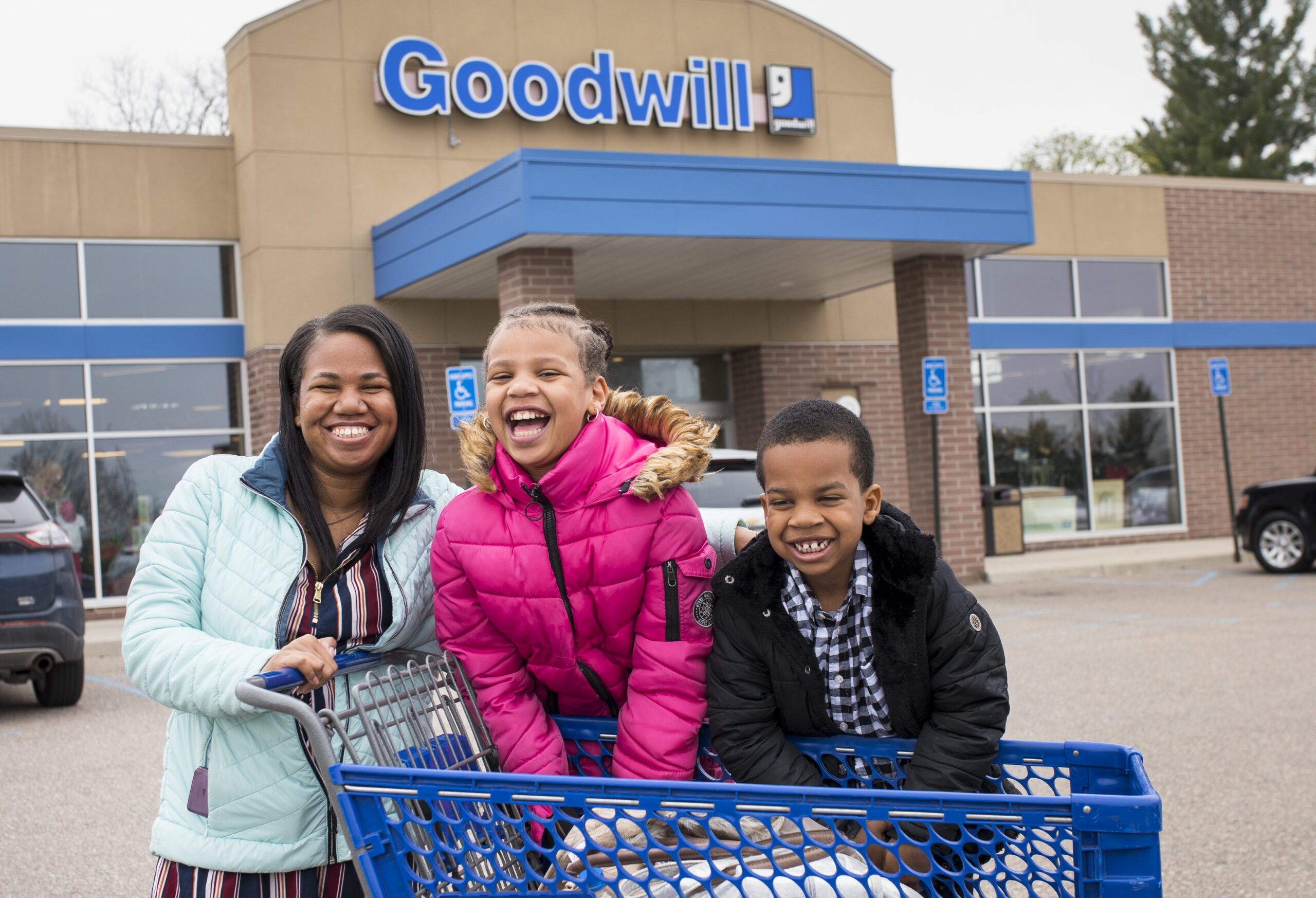 Family leaving Goodwill store with shopping cart
